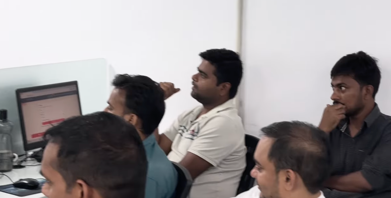 Corporate office में 4-5 male professionals deeply engaged — एक सर पर हाथ रखे, दूसरा सोचते हुए। AI session में absorbed।