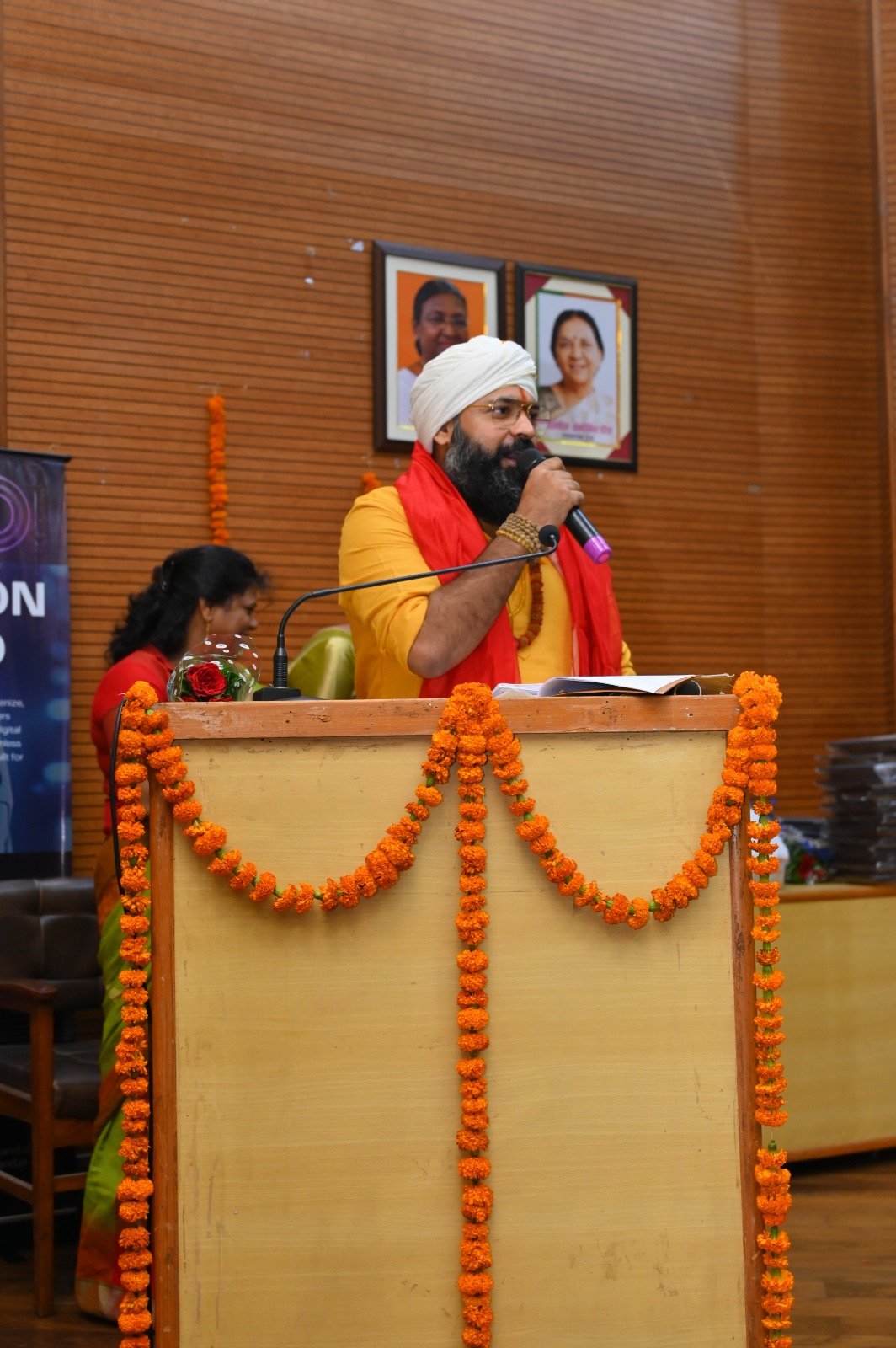 Kabeer Ji Maharaj Lucknow Sahkarita Bhawan में गेंदे के फूलों से सजे podium पर keynote देते हुए — Shakti Samman 2025 में मुख्य अतिथि